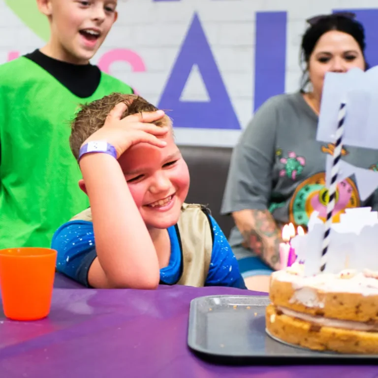 Happy child seeing his birthday cake at his trampoline park birthday party.